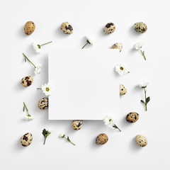 Quail eggs and white flower top view with square paper frame
