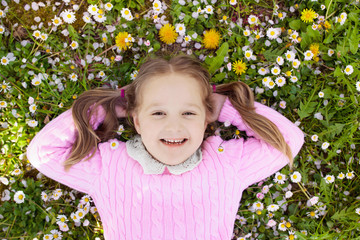 Child on green grass lawn with summer flowers