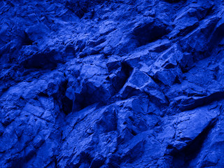 Abstract blue background. Toned mountain texture. Close-up. The combination of bright blue and rough stone surface. Colorful rock background.