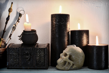Burning candles with wax skull and withc ritual objects.
