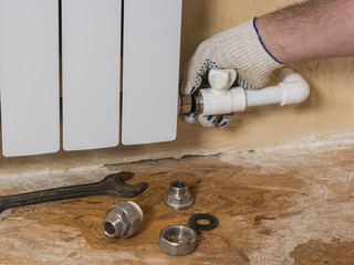 A man turns off a leaking radiator in a private home. Accident of the heating system of a private...