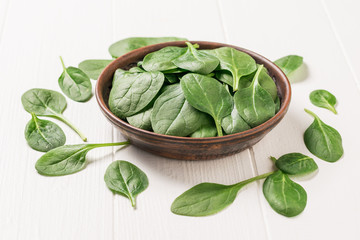 A large number of spinach leaves on a white wooden table. Food for fitness. The view from the top.