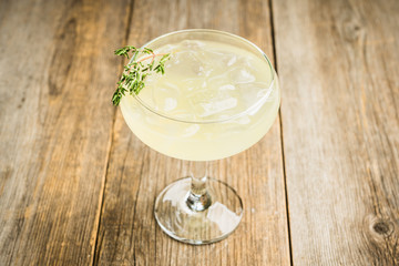 Tasty and little bitter lemon cocktail with slice of fresh lemon and thyme. Selective focus....