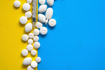 top view of white pills and syringe on color background 