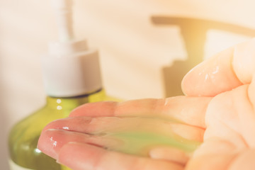 Female hand using liquid soap from a dispenser. Green cleanser in the fingers