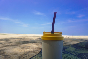 Stainless steel coffee mug on the sand behind the sea