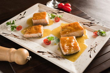 Salmon slices in mustard sauce on a rectangular white plate