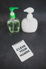 keep clean to fight bacteria and viruses, hand sanitizer and liquid soap next to memo with Clean your Hands text