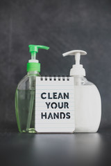 keep clean to fight bacteria and viruses, hand sanitizer and liquid soap next to memo with Clean your Hands text