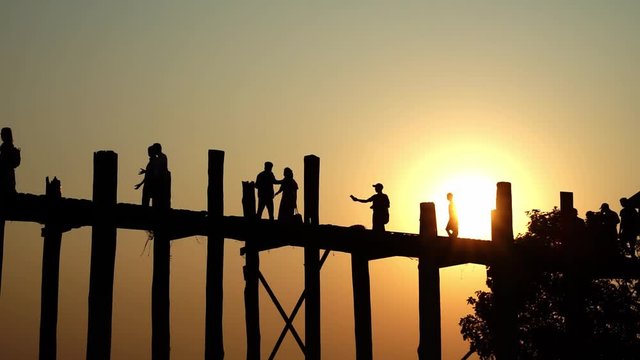 Silhouette of peoples at U-Bein oldes teakwood bridge in the world is made from the remains of a royal palace crossing Taungthaman Lake. Amarapura, Mandalay, Myanmar