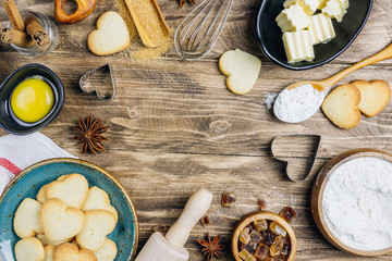 Valentine's Day baking culinary background. Ingredients for cooking on wooden kitchen table, baking recipe for pastry. Heart shape cookies.