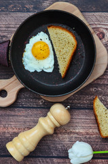 Fried egg and slices of bread , pepper mill on a wooden table. Morning breakfast and healthy food.