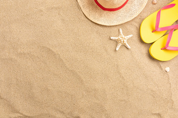 Fototapeta na wymiar Flip flops, straw hat, on sand background. Beach vacation concept .Top view with copy space.
