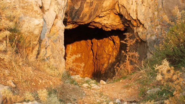 Sun is shining on the entrance of a cave at golden hour at Feraklos Castle, Rhodes, Greece