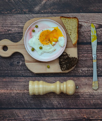 Fried egg and slices of bread , pepper mill on a wooden table. Morning breakfast and healthy food.