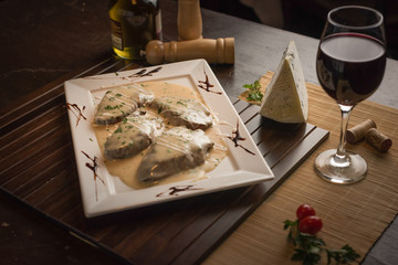 filet mignon with gorgonzola cheese sauce, with red wine and green seasoning on a white rectangular plate - obrazy, fototapety, plakaty