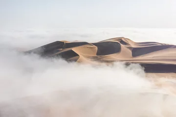 Deurstickers Top van een enorme zandduin die na zonsopgang uit een dikke mistwolk tevoorschijn komt. Liwa-woestijn, Abu Dhabi, Verenigde Arabische Emiraten. © Kertu