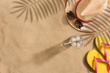 Summer vacation composition. Hat, sunglasses and flip flops on sand background. Harsh light with...