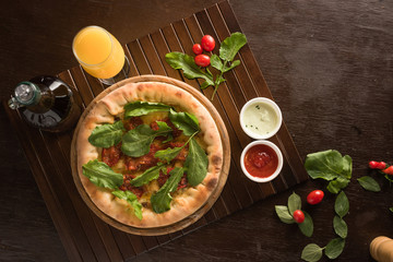 Dried tomato pizza with arugula, accompanied by orange juice