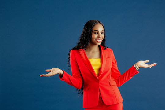 Portrait Of A  Young Smiling Woman In Red Business Suit With Arms Out,  Isolated On Blue Background