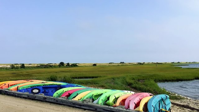 Row of multicolored kayaks by small bridge near dunes of east beach Cape Poge wildlife refuge Chappaquiddick island Martha's Vineyard summer wide