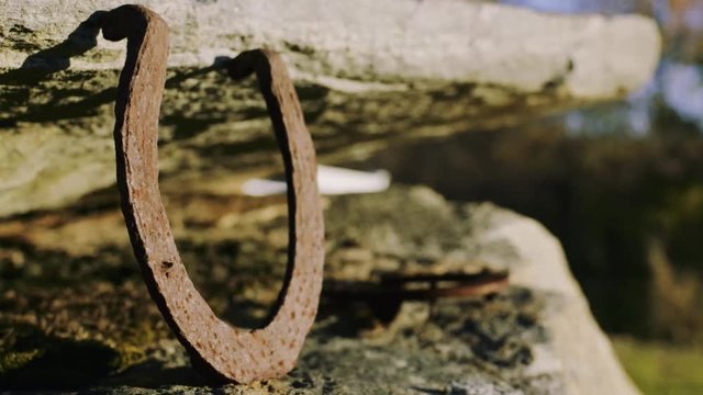 Rusted horseshoe on rock formation sunlit close-up IV