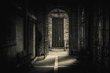 Obraz premium Drawing-like view of scary passage leading to an old brick arch with a rusty open iron gate, heading to a broken blind. Light trails and shadows mixed in spooky ways.