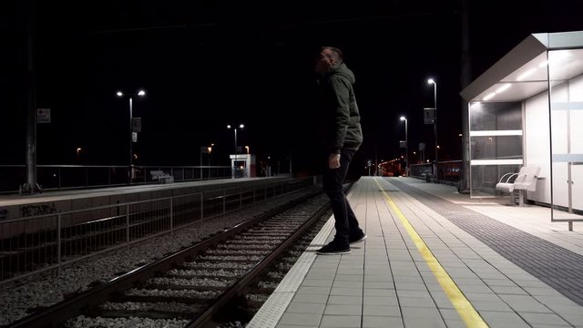 Depression Man Suicide Thoughts Concept on a train station. Night time