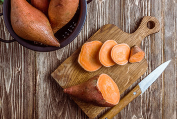 Organic farm sweet potato on rustic wooden background. Healthy eating and zero waste concept. Top...