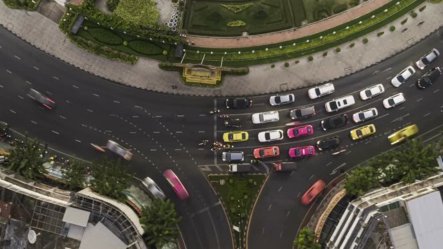 Hyperlapse timelapse of night city traffic on 4-way stop street intersection circle roundabout in bangkok, thailand. 4K UHD horizontal aerial view.