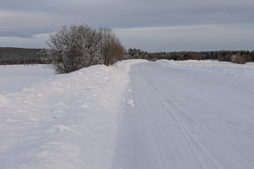 Fototapeta na wymiar Winter landscape - snow-covered road and the clouds in the sky