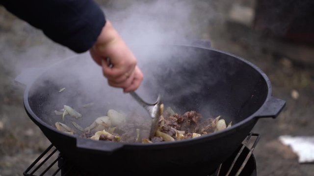 cooking mutton with onions in a cauldron