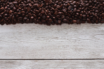 Dark roasted coffee beans border on white wooden table. Natural ingredient, agriculture, coffee shop, crop, backdrop concept