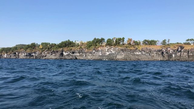 White Sailing Catamaran Yacht walking near Jeju island. Surf, waves and rocks from yacht boat.
