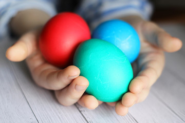 three colored Easter eggs in the hands of a child