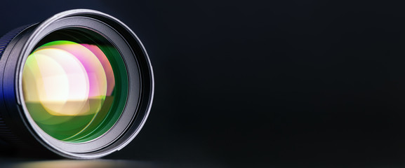 Banner. The camera lens with multi-colored illumination on a black background.  Right place for...