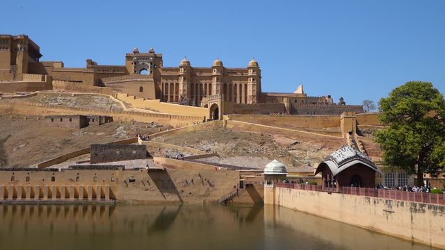 Panning shot of the blue green water and kesar kyari bagh island in the maota lake in Amber palace in Jaipur