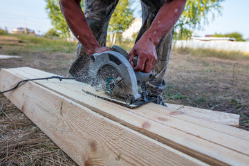 A worker saws a wooden beam.