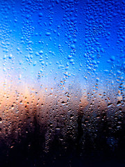 Drops of water on a glass in blue in the morning.