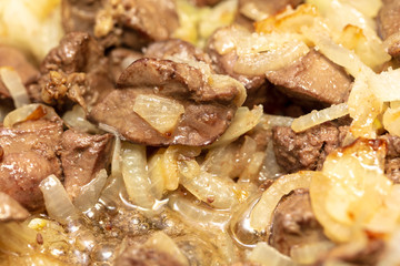 Chicken liver is fried in a pan.