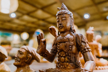 Wooden sculptures of various profiles with natural finishing are displayed as souvenirs in Bali.