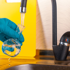 water purification specialist tap water pours into a glass flask.