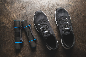 Fitness concept. Black sports shoes and dumbbells.