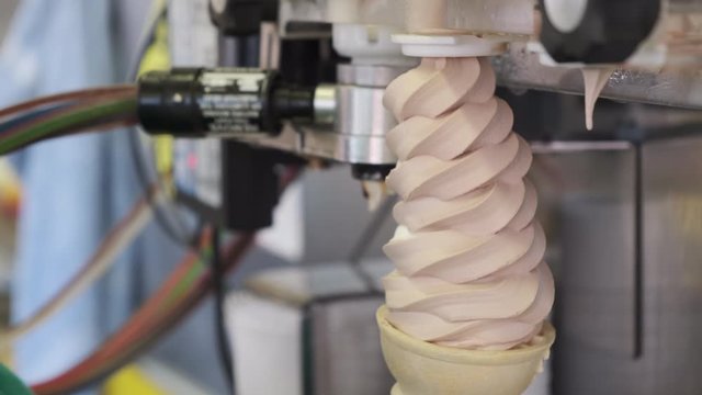 Close up of chocolate and vanilla ice cream fills into cone by special machine
