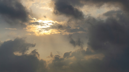 Upward view to the gray cloudy sky around the sun and orange light of the sunshine