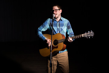 Obraz premium Musician in a plaid shirt plays on an guitar. Low key portrait