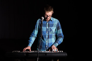 Musician man play keyboard on dark background