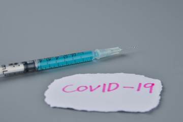 Coronavirus (COVID-19) vaccine with injection syringe isolated on gray background.