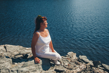 the girl is sitting on the rocks by the lake. Woman sunbathing on the beach. The concept of recreation, tourism