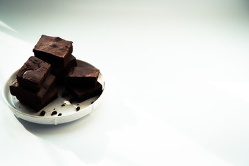 Chocolate brownie sliced into square slices on a white plate.